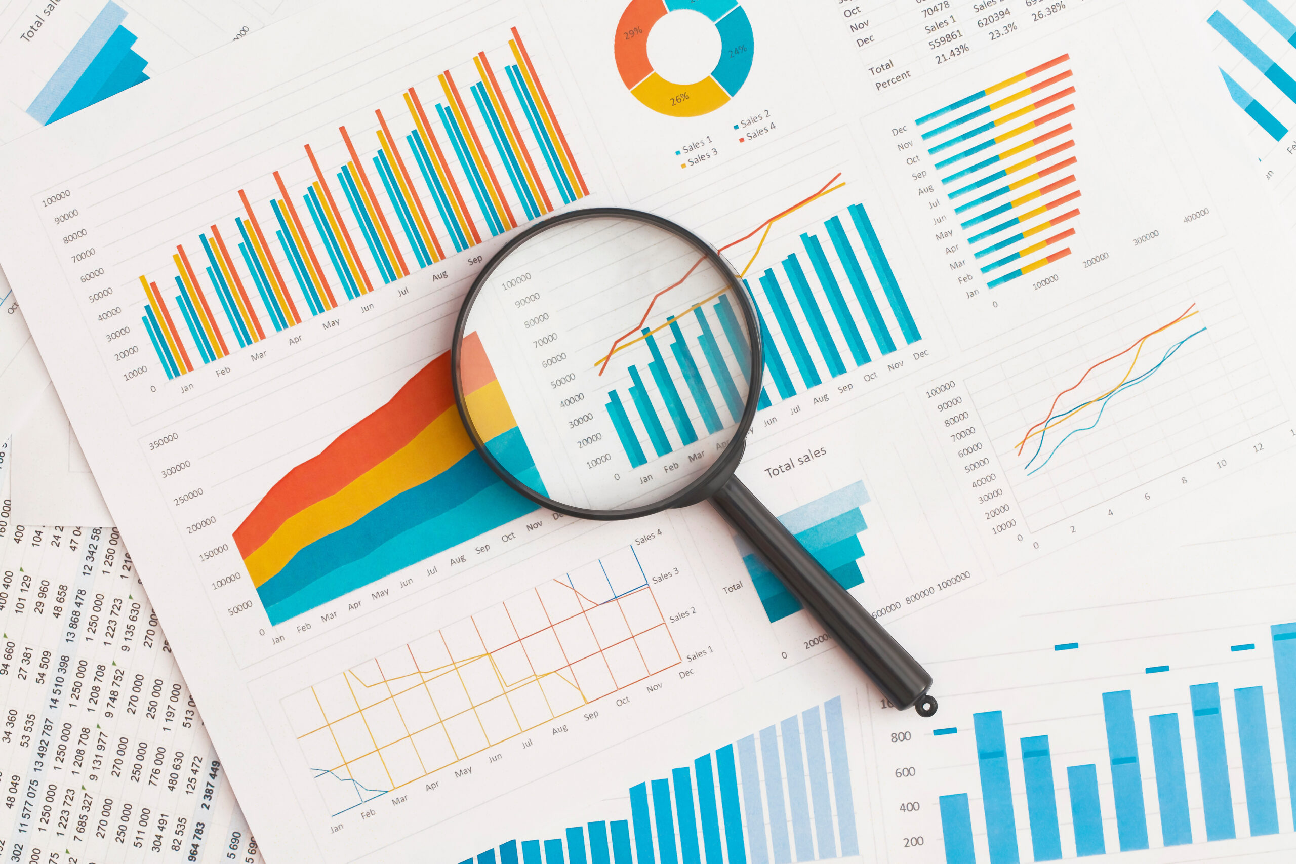 Business graphs, charts and magnifying glass on table. Financial